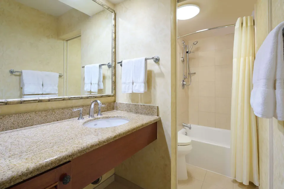 Guest room bathroom with vanity and tub shower at Outrigger Waikiki Beach Resort.