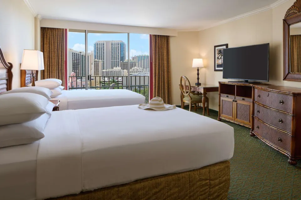 Two-bed guest room with balcony and city view at Outrigger Waikiki Beach Resort.