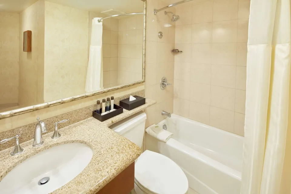 Suite bathroom with vanity and tub shower at Outrigger Waikiki Beach Resort.