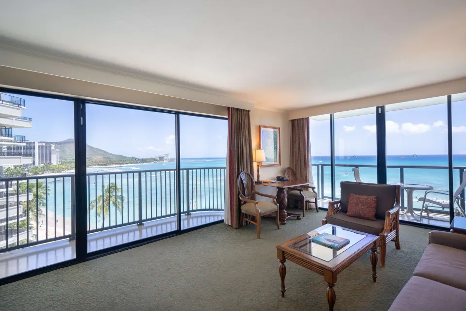 Oceanfront suite living area with sofa bed and wraparound views at Outrigger Waikiki Beach Resort.