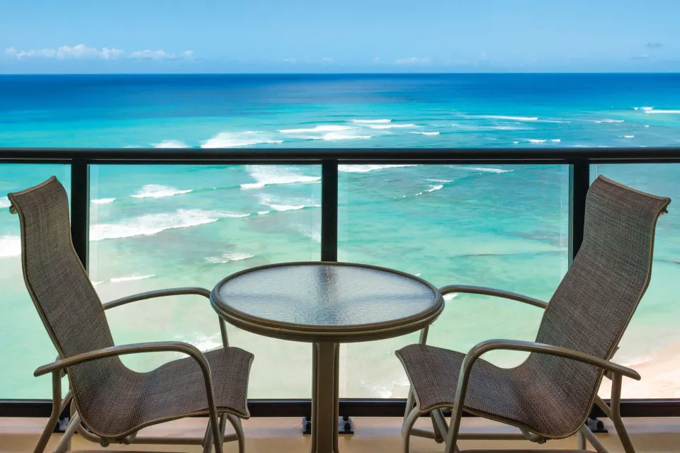 Balcony table and chairs facing the ocean at Outrigger Waikiki Beach Resort.