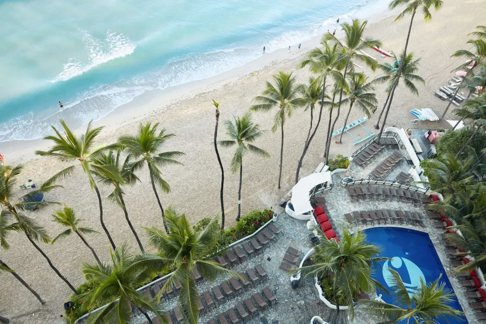 Suite view of beach, palms, and pool deck at Outrigger Waikiki Beach Resort.