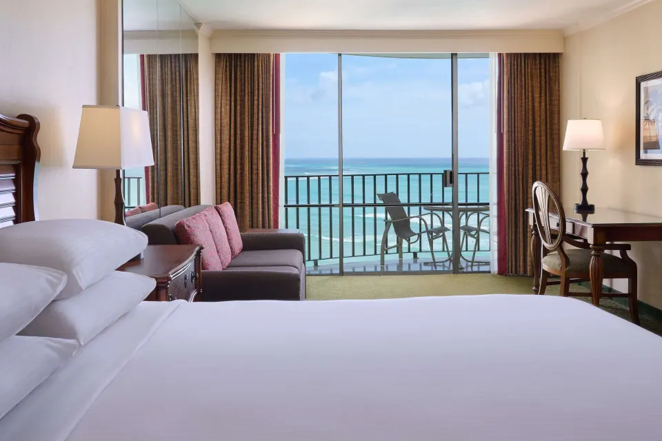 Suite sofa bed, king bed, and ocean balcony at Outrigger Waikiki Beach Resort.