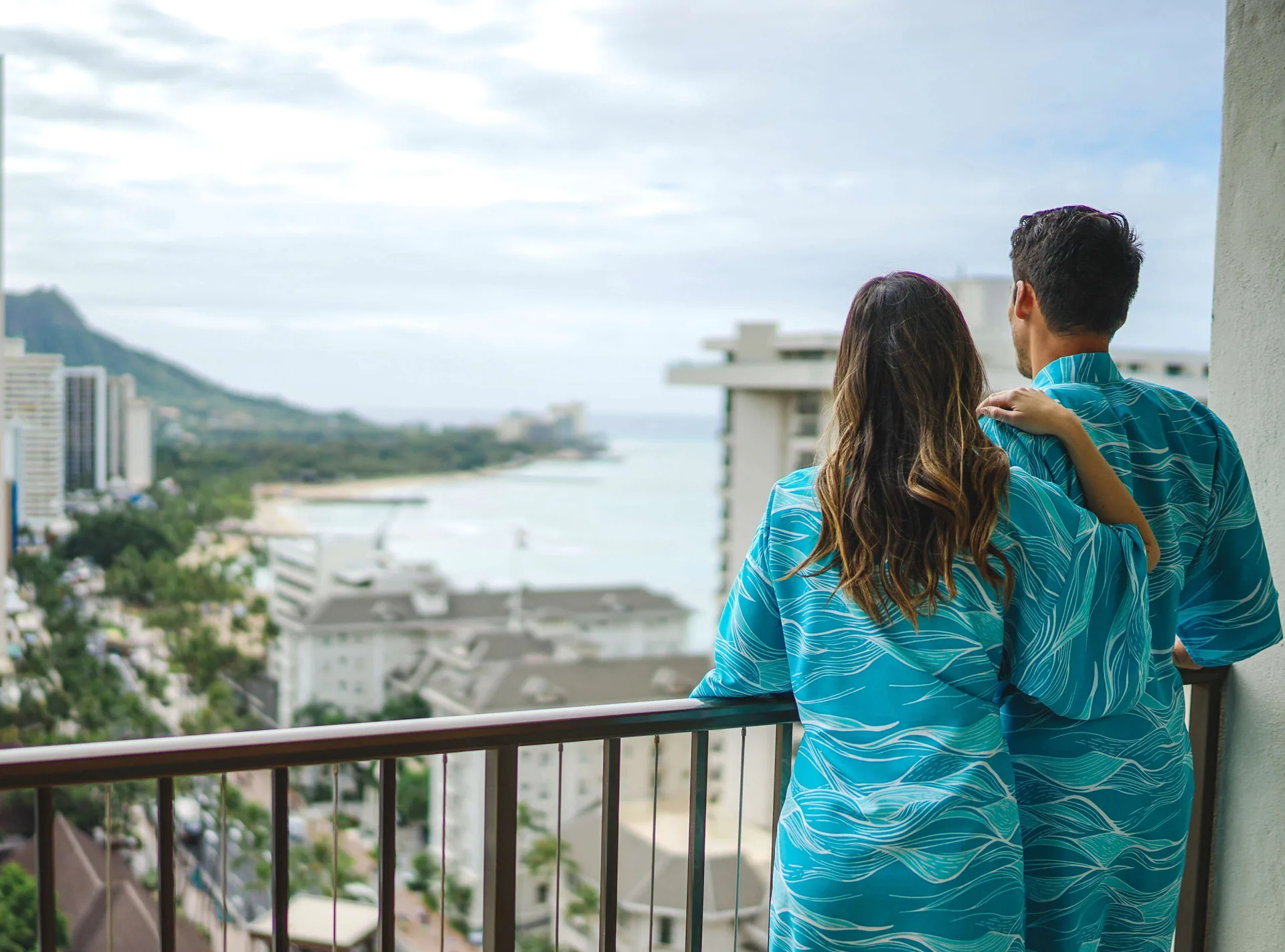 Couple at a balcony railing overlooking Waikiki at OUTRIGGER Waikiki Beachcomber Hotel.