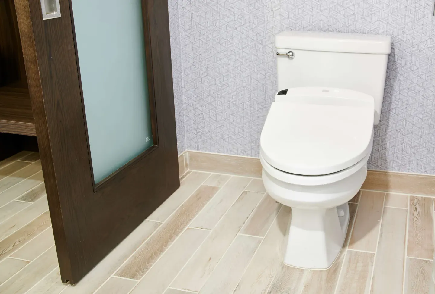 Guest bathroom toilet, patterned wall, and frosted glass door at OUTRIGGER Waikiki Beachcomber Hotel.
