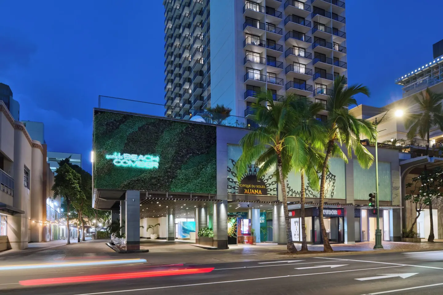 Night exterior of OUTRIGGER Waikiki Beachcomber Hotel along a city street.