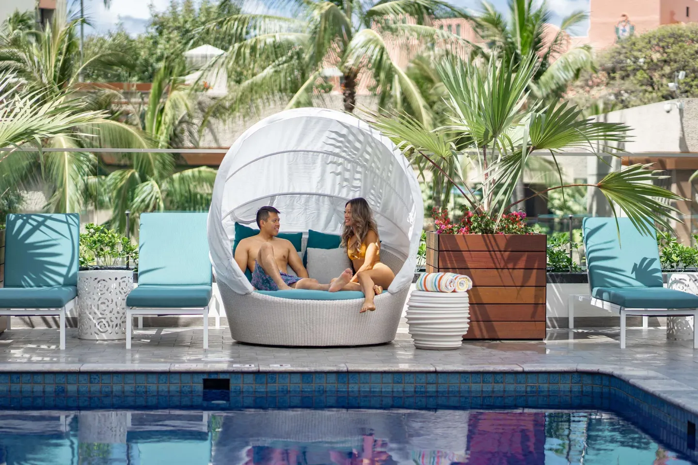 Guests relaxing in a white pool cabana at OUTRIGGER Waikiki Beachcomber Hotel.