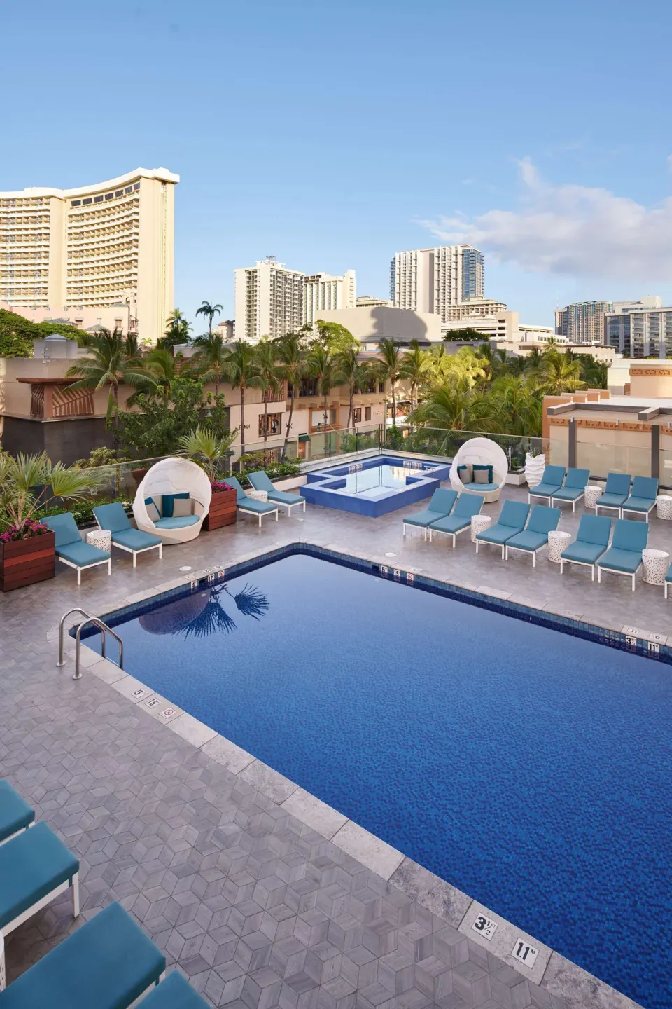 Pool deck with lounge chairs and city views at OUTRIGGER Waikiki Beachcomber Hotel.