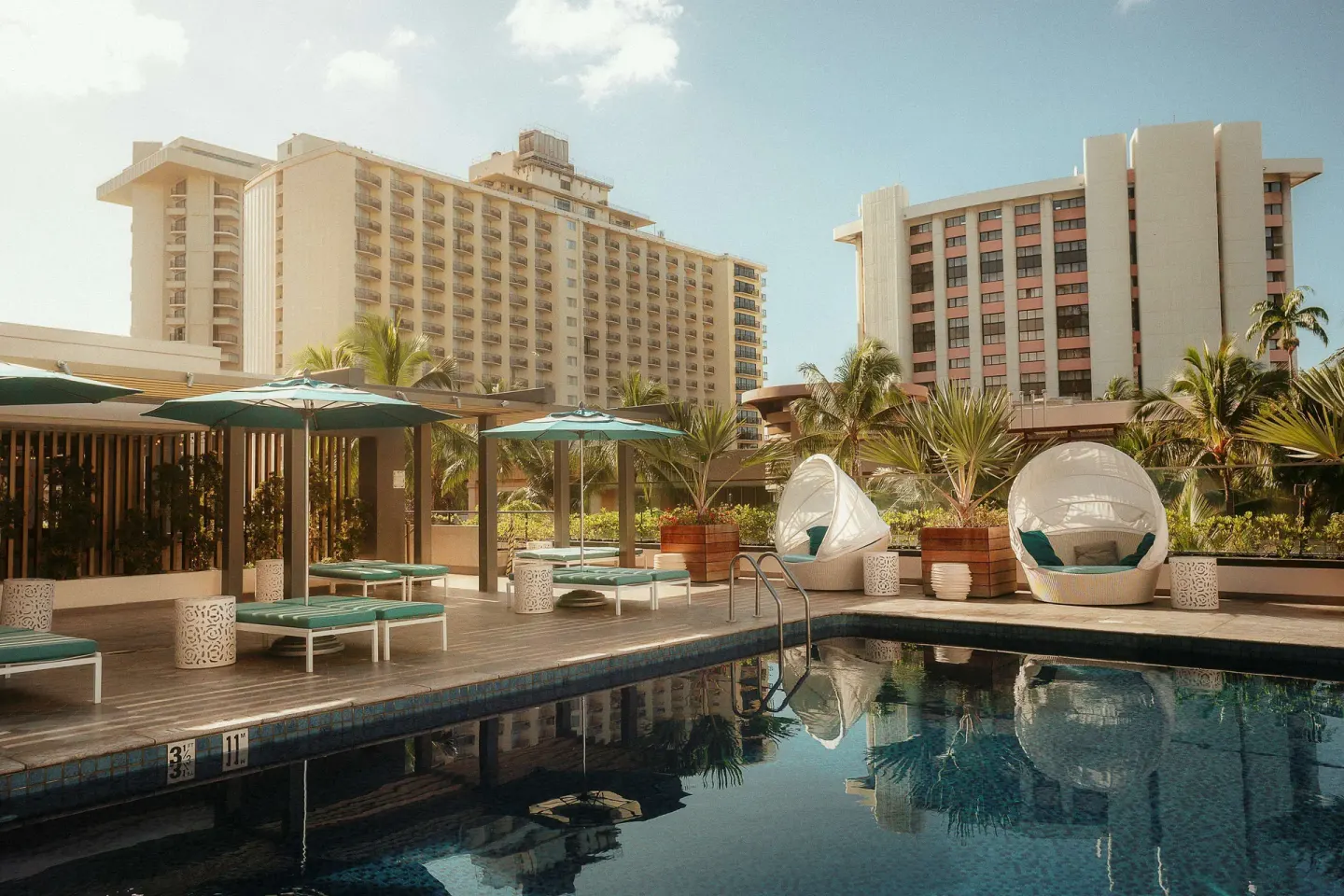 Pool deck with loungers and cabanas at OUTRIGGER Waikiki Beachcomber Hotel.