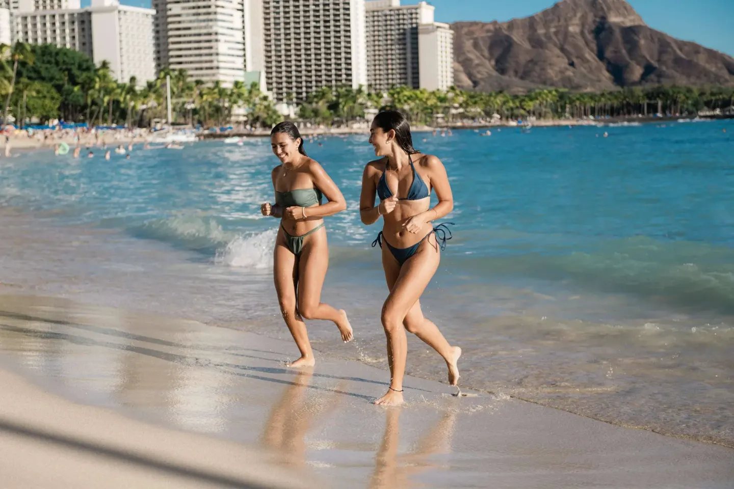 Two people jog along Waikiki Beach near OUTRIGGER Waikiki Beachcomber Hotel.