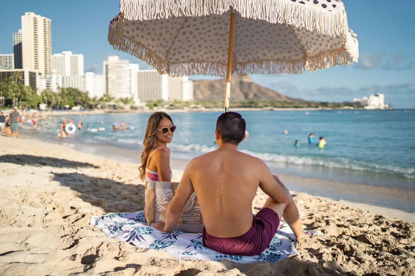 Beachgoers sit under an umbrella near OUTRIGGER Waikiki Beachcomber Hotel.