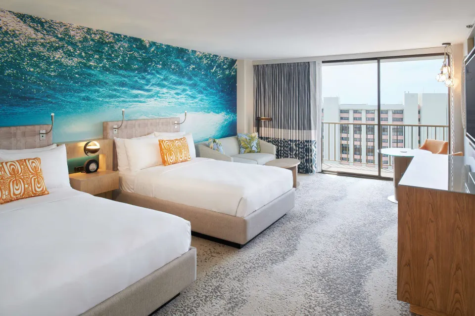 Junior Suite with two beds, sofa, dresser and balcony doors at OUTRIGGER Waikiki Beachcomber Hotel.
