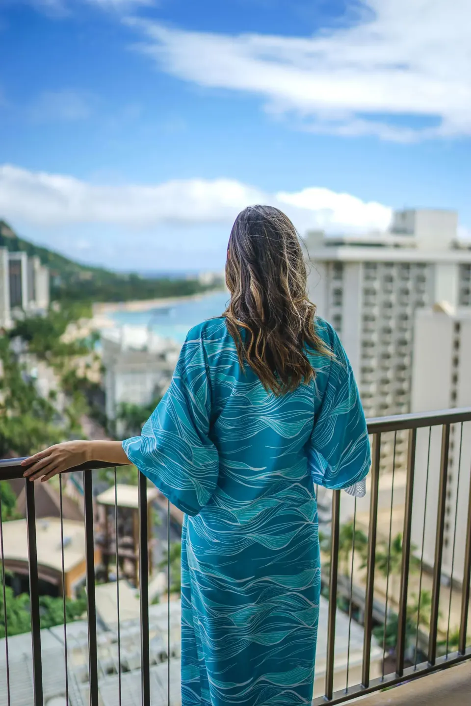 Guest on an Ocean View room balcony at OUTRIGGER Waikiki Beachcomber Hotel facing Waikiki.