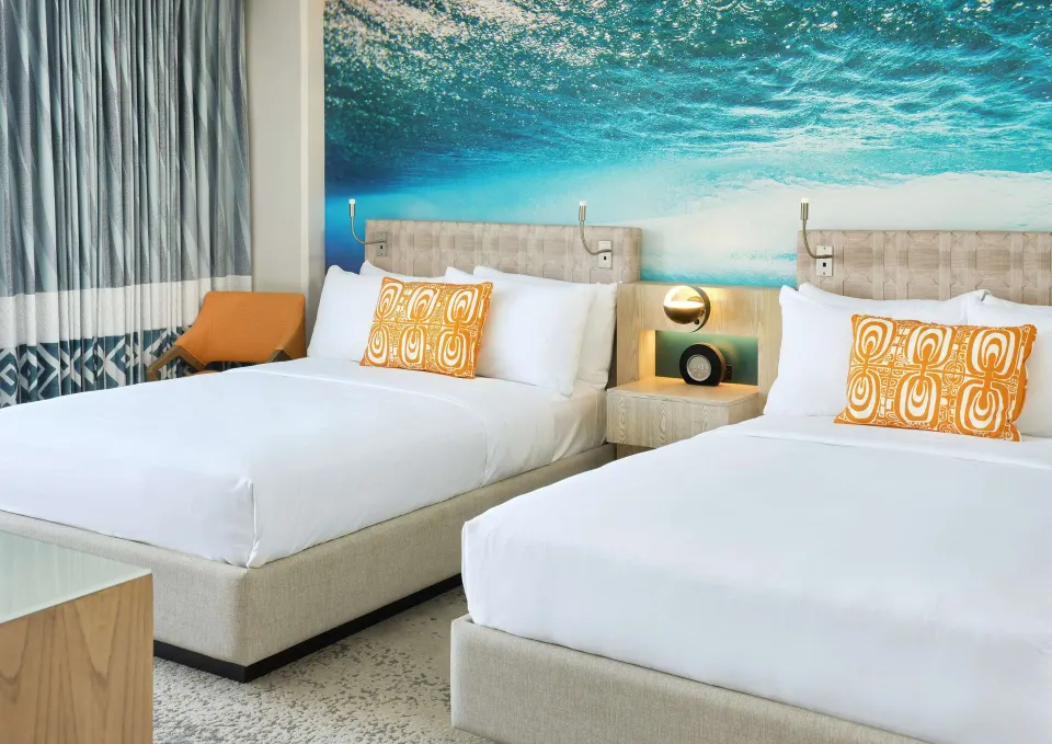 Two beds with ocean mural in a Partial Ocean View room at OUTRIGGER Waikiki Beachcomber Hotel.