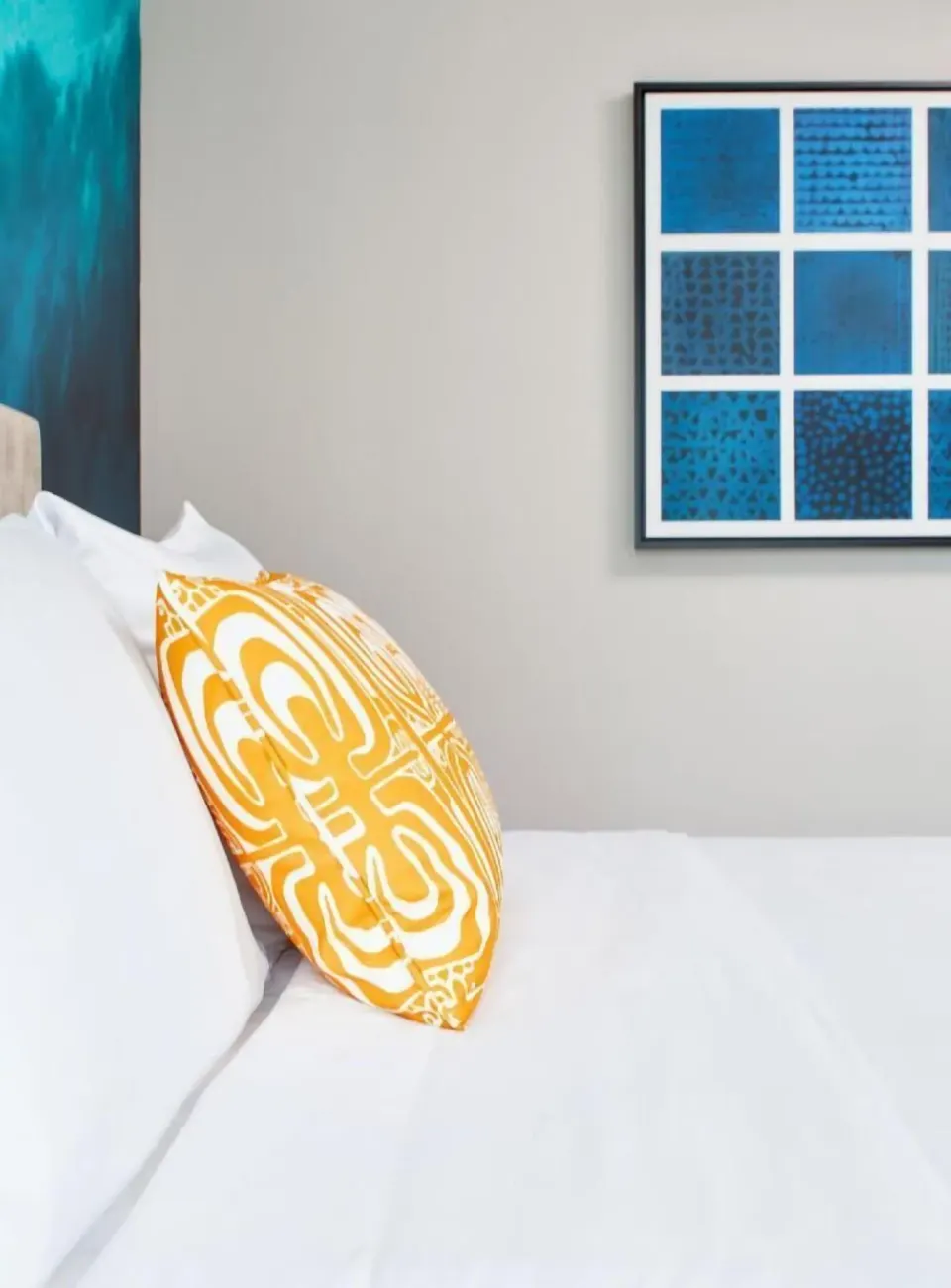 Bed corner with orange pillow and wall art in a Partial Ocean View room at Outrigger Waikiki Beachcomber Hotel.