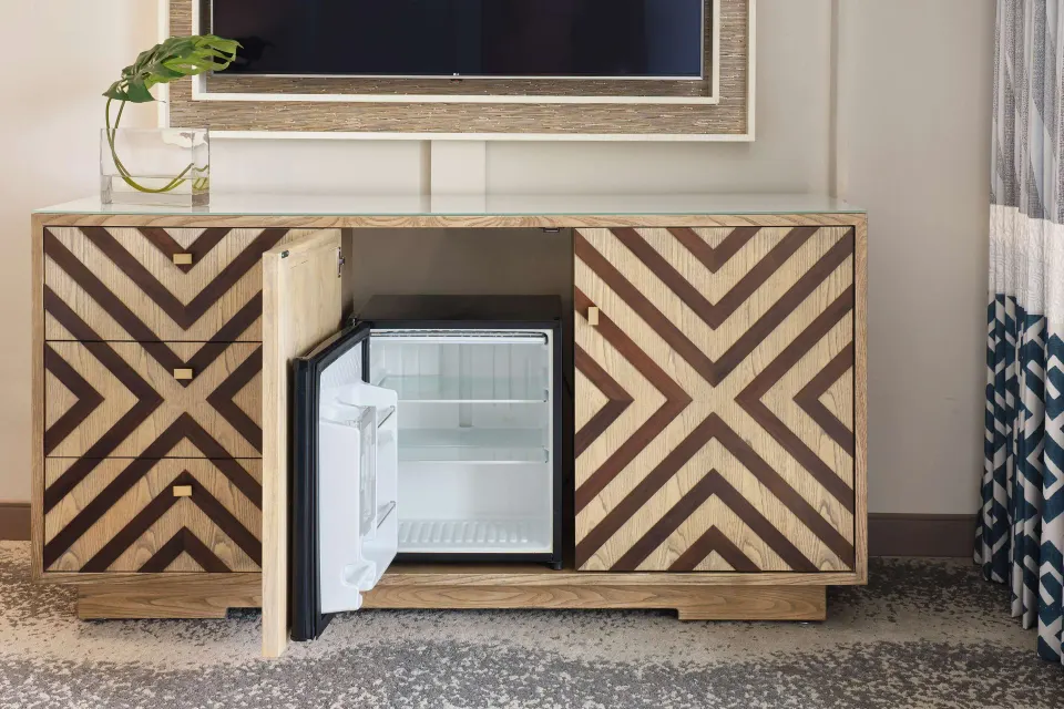 Guest room media cabinet with open mini refrigerator at OUTRIGGER Waikiki Beachcomber Hotel.
