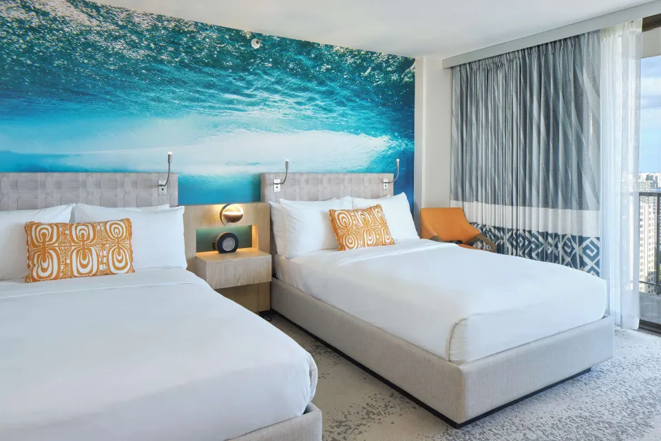 Two beds and balcony window in a guest room at OUTRIGGER Waikiki Beachcomber Hotel.
