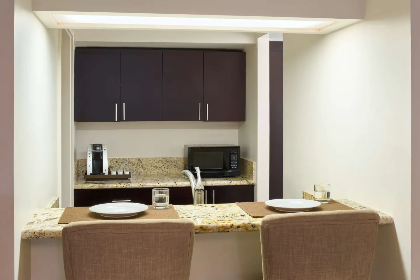 Suite kitchenette with breakfast counter and two place settings at OUTRIGGER Waikiki Beachcomber Hotel.