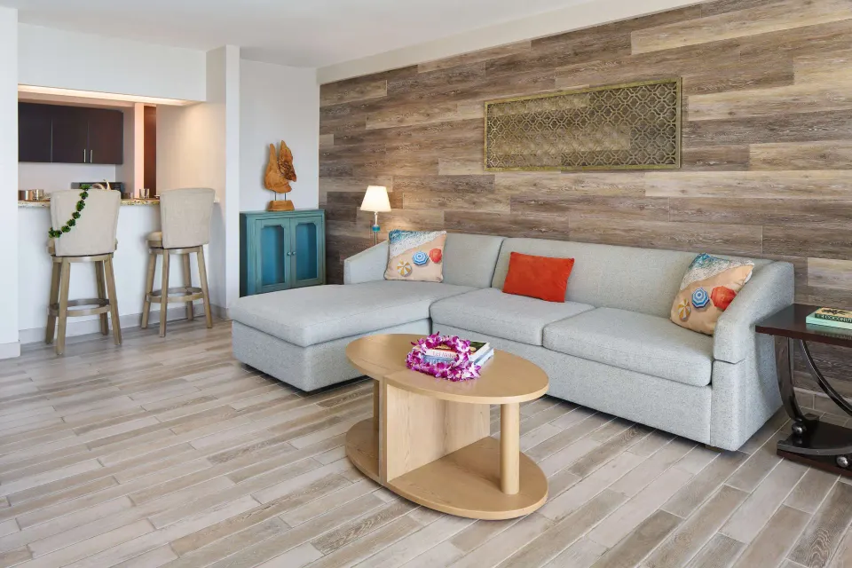 Suite living area with sectional sofa and kitchenette at OUTRIGGER Waikiki Beachcomber Hotel.