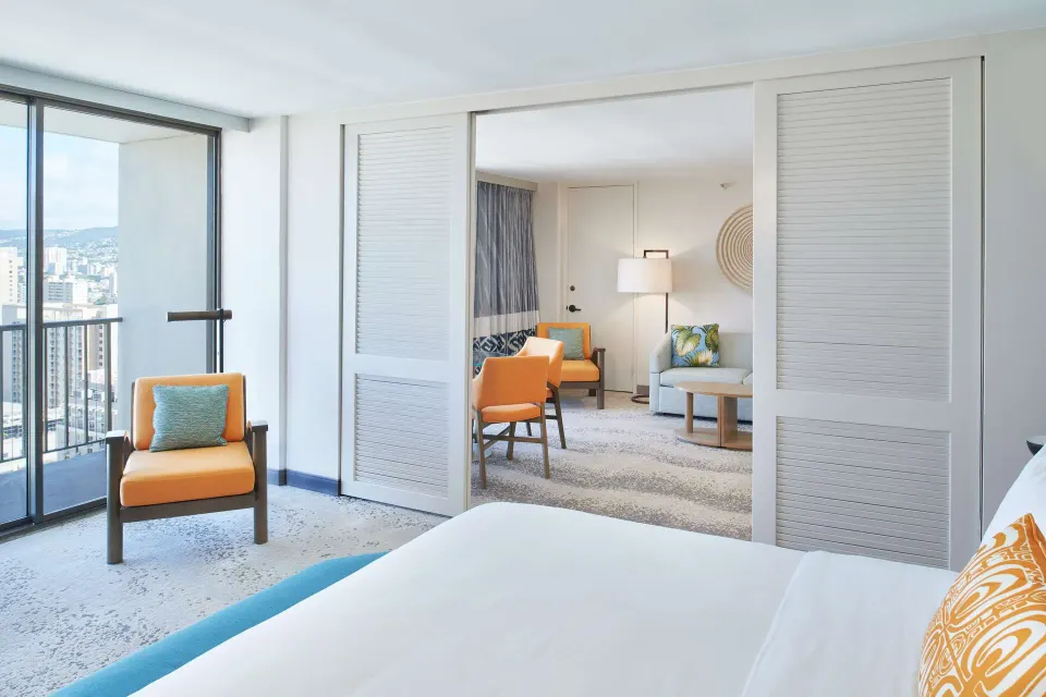 Ocean View Suite bedroom with balcony and sitting room at OUTRIGGER Waikiki Beachcomber Hotel.