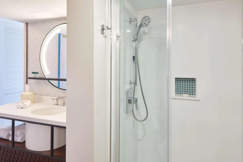 Waikiki View bathroom shower at OUTRIGGER Waikiki Beachcomber Hotel with glass door and vanity nearby.