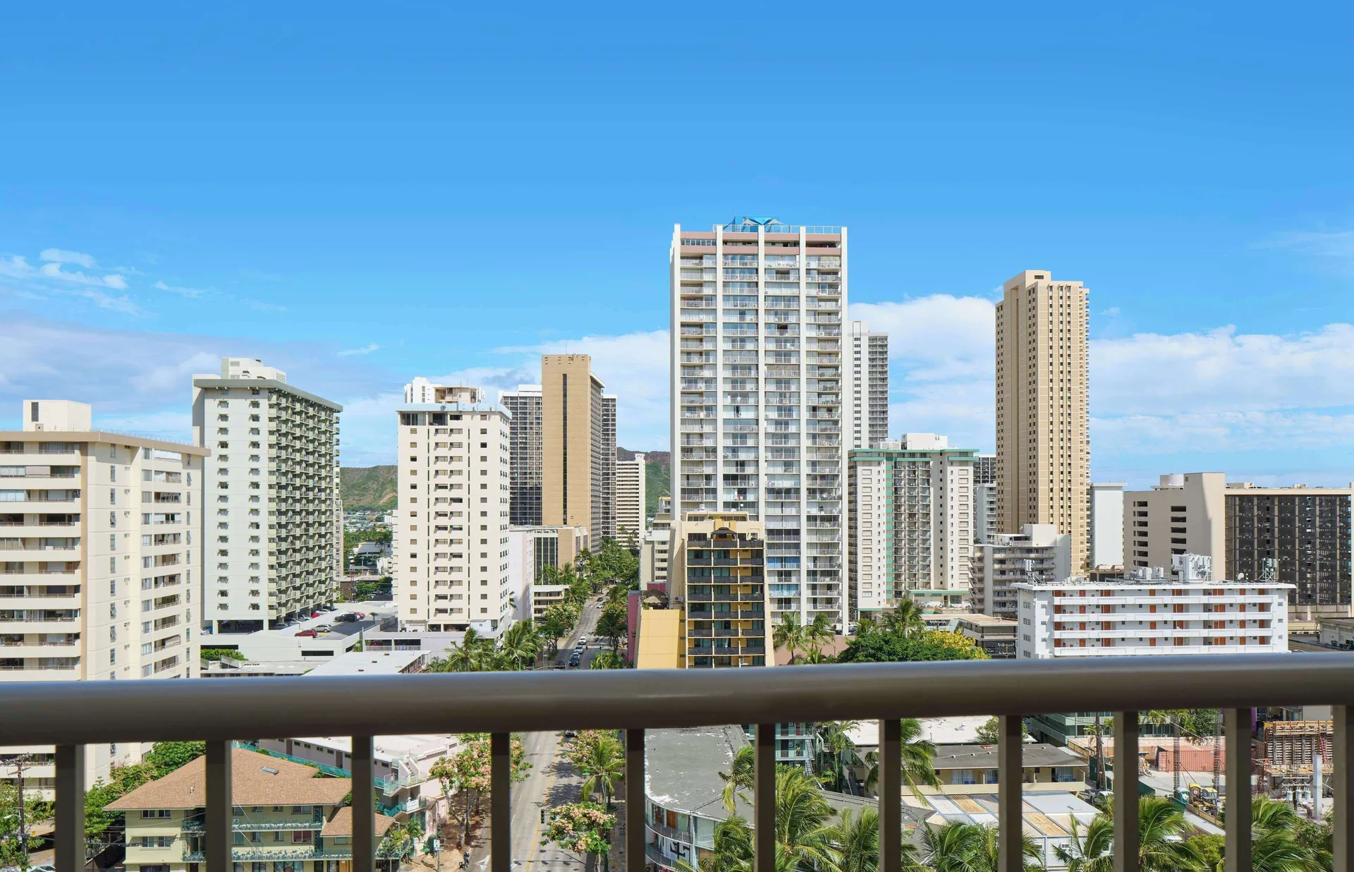 A balcony view faces Waikiki high-rises and palm-lined streets at OUTRIGGER Waikiki Paradise Hotel.