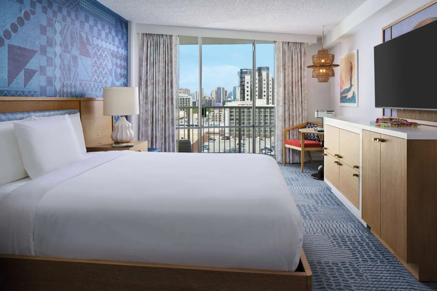 King bed guest room with city-facing balcony at OUTRIGGER Waikiki Paradise Hotel.