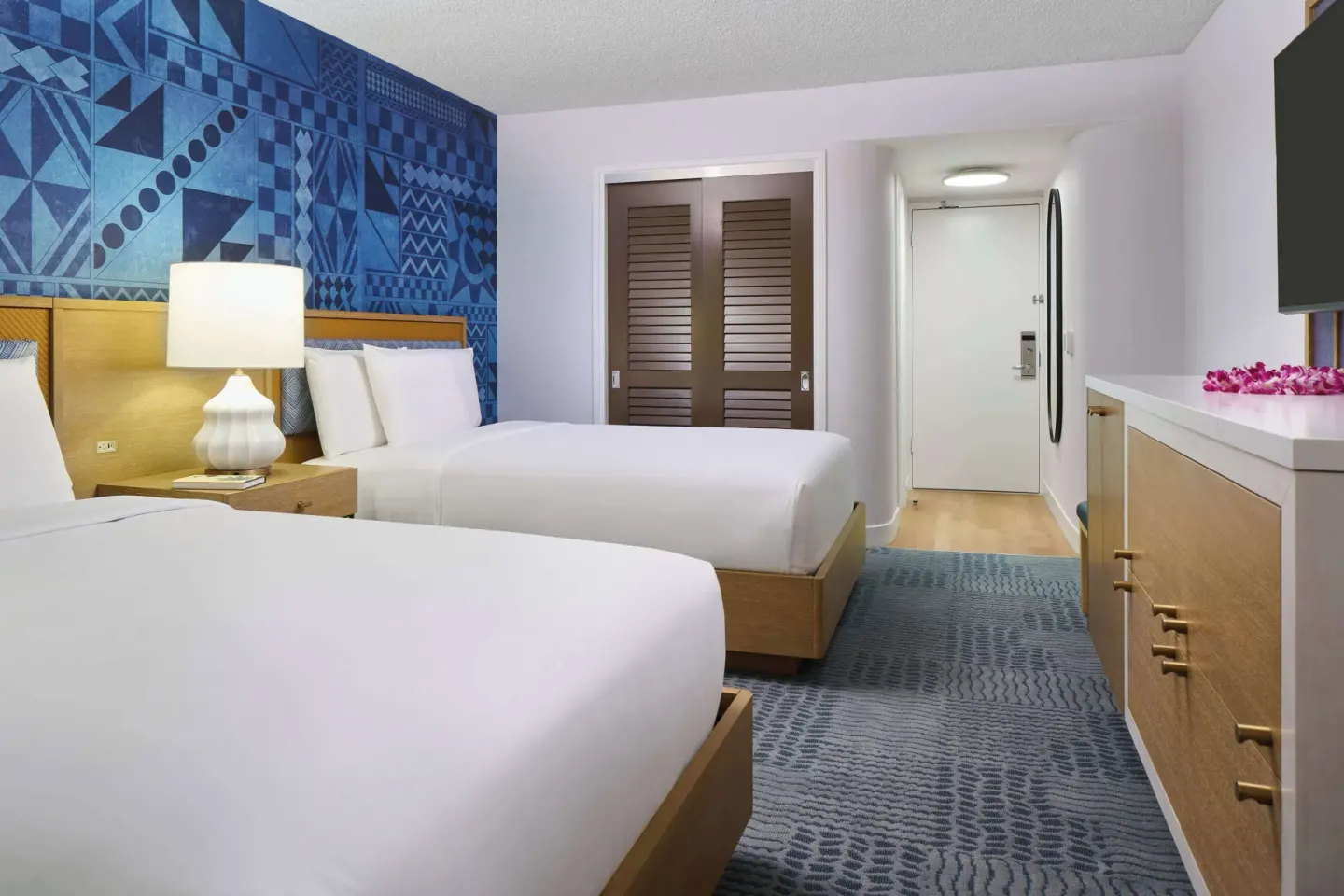 Two-bed guest room with dresser and entry door at OUTRIGGER Waikiki Paradise Hotel.