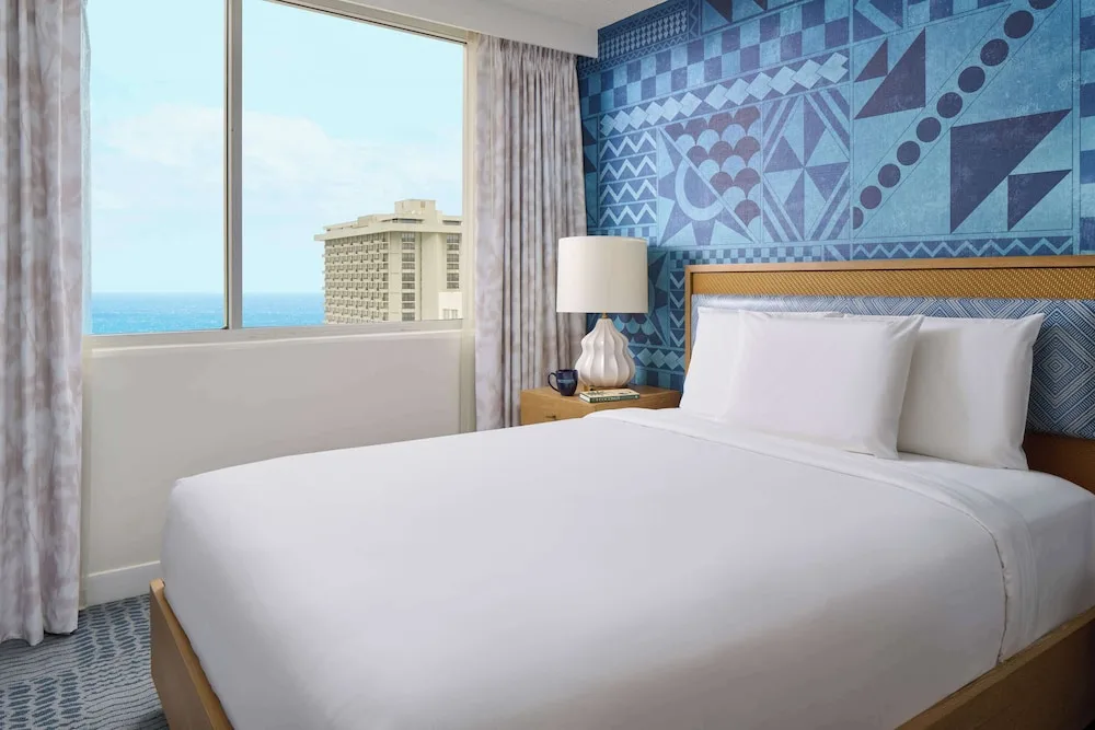 King-bed guest room with ocean glimpse at OUTRIGGER Waikiki Paradise Hotel.