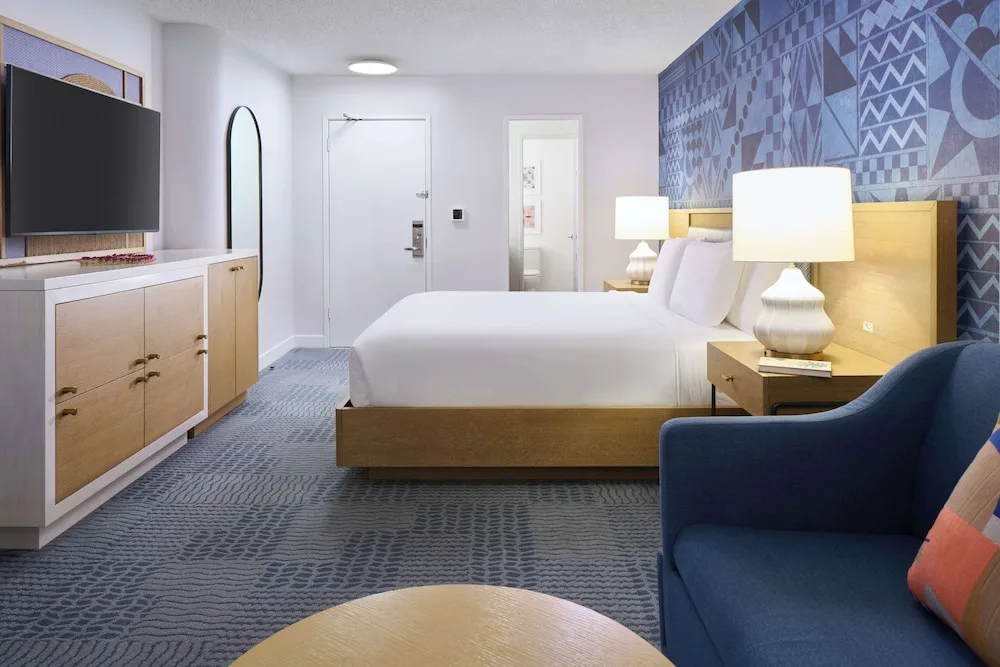 King bed guest room with blue lounge chair at OUTRIGGER Waikiki Paradise Hotel.