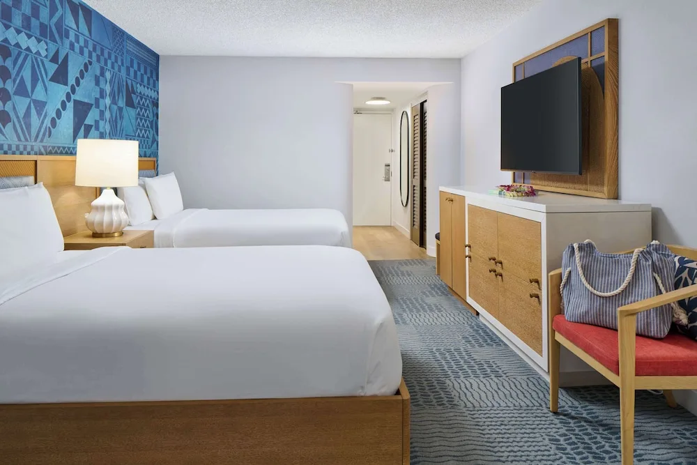 Two-bed guest room with dresser and accent chair at OUTRIGGER Waikiki Paradise Hotel.