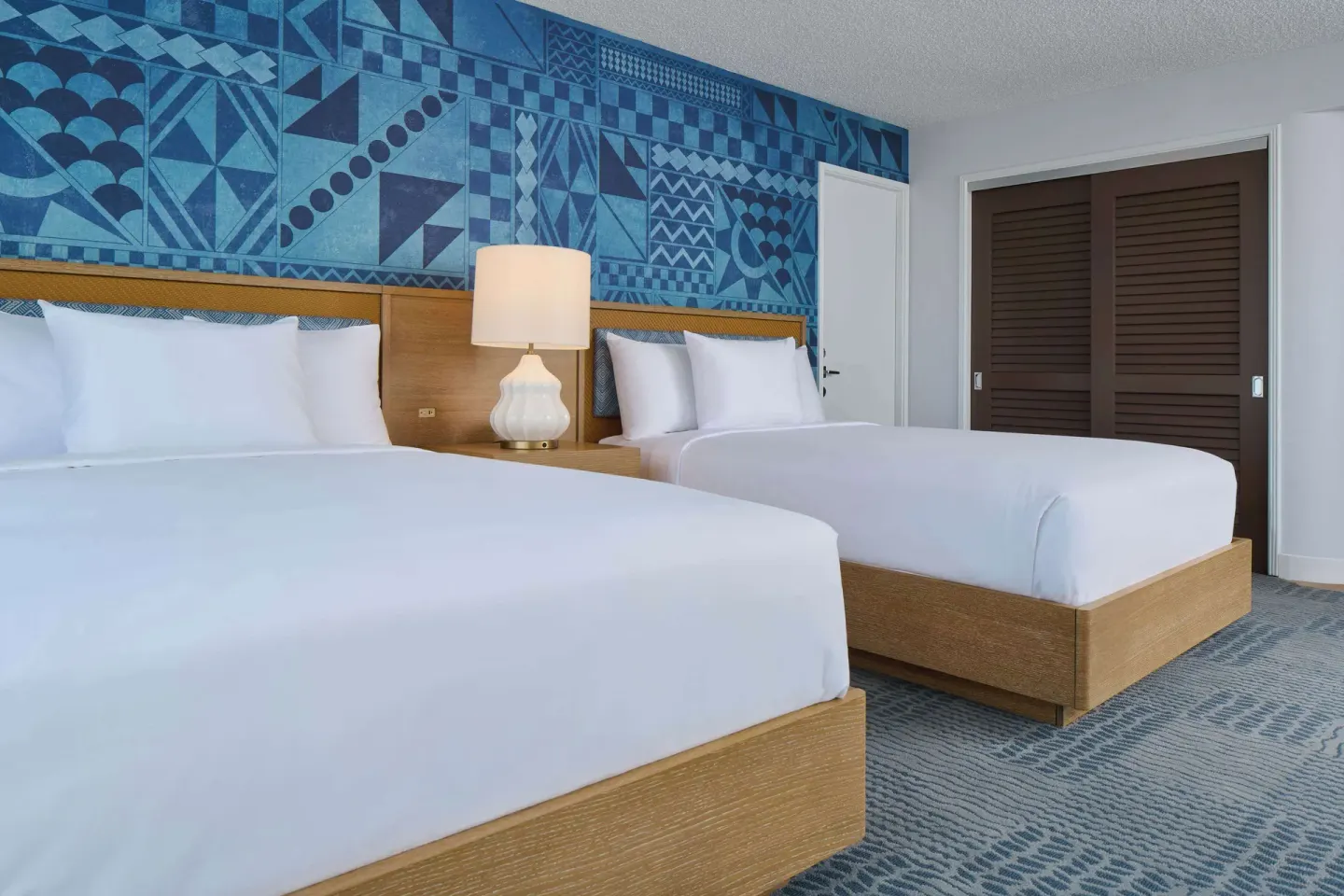 Two-bed guest room with blue patterned wall at OUTRIGGER Waikiki Paradise Hotel.