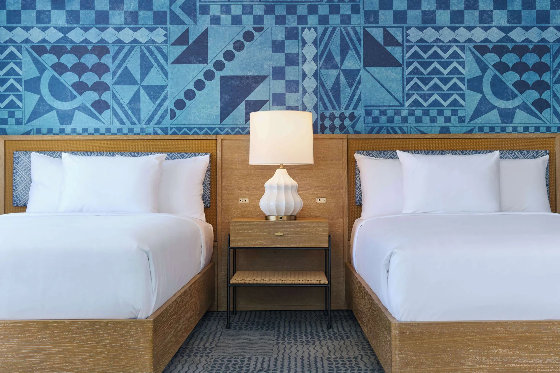 Two guest room beds with a blue patterned mural at OUTRIGGER Waikiki Paradise Hotel.