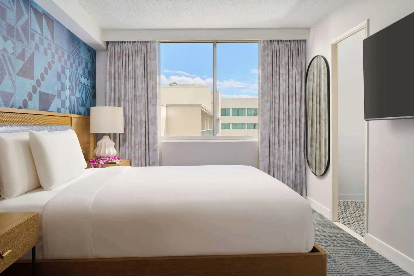 King bed guest room with window and oval mirror at OUTRIGGER Waikiki Paradise Hotel.