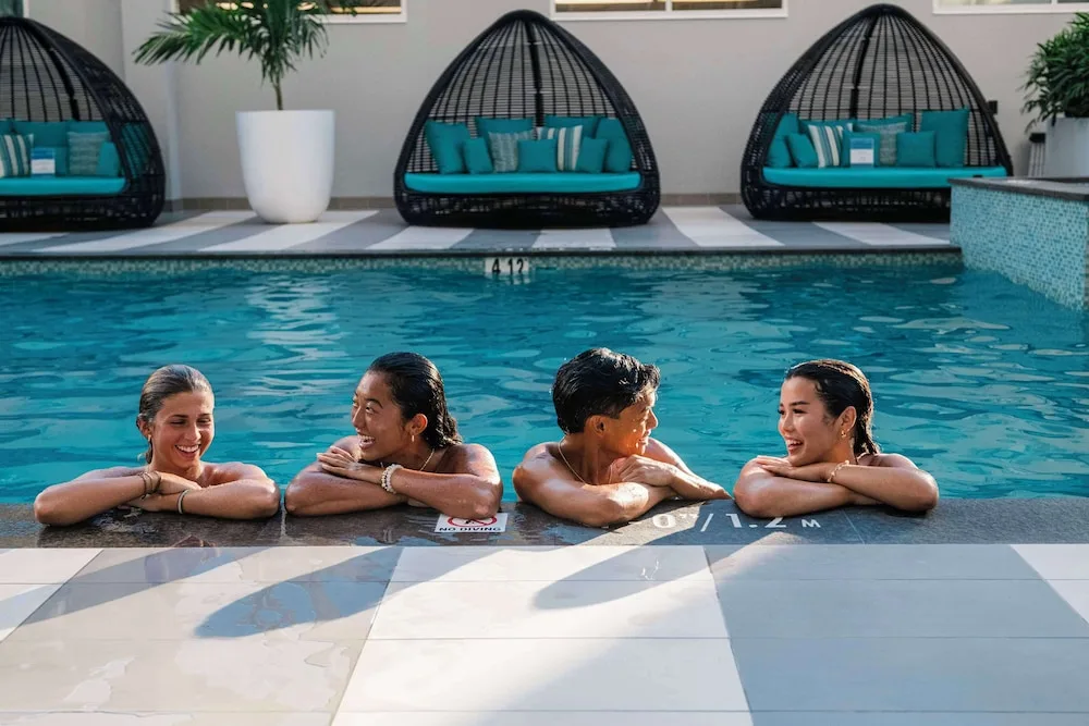 Guests relaxing at the pool edge at OUTRIGGER Waikiki Paradise Hotel.