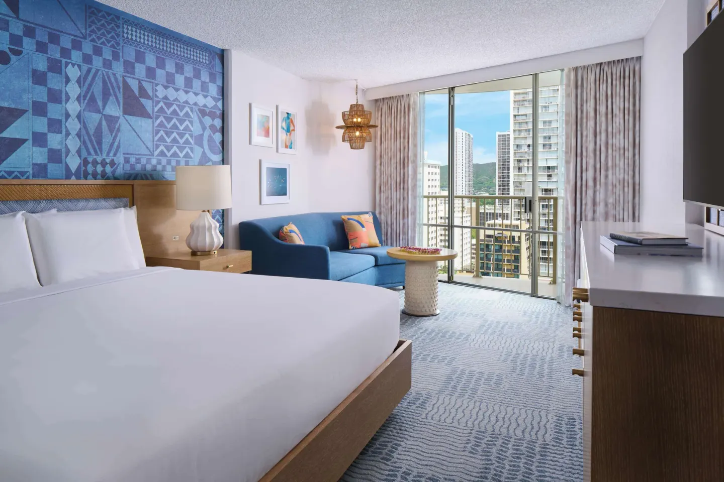 Waikiki view king guest room with blue sofa at OUTRIGGER Waikiki Paradise Hotel.