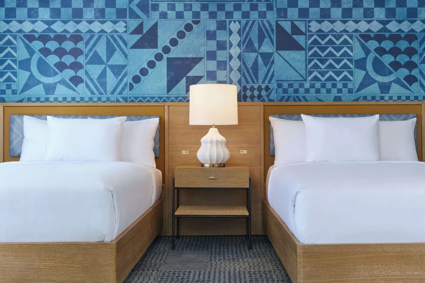 Two beds and a central nightstand in a guest room at OUTRIGGER Waikiki Paradise Hotel.