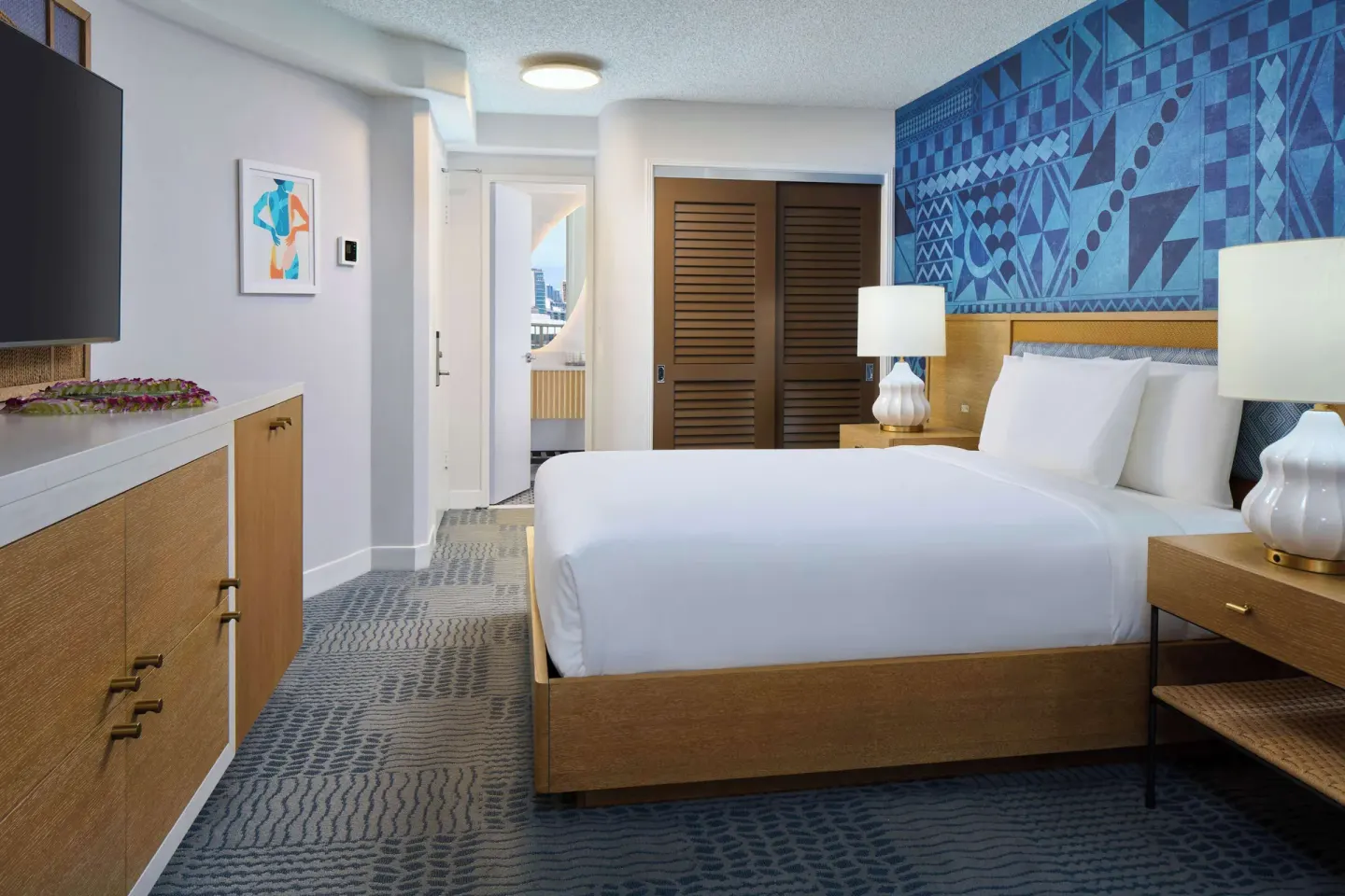 King bed guest room with dresser, lamps and closet doors at OUTRIGGER Waikiki Paradise Hotel.