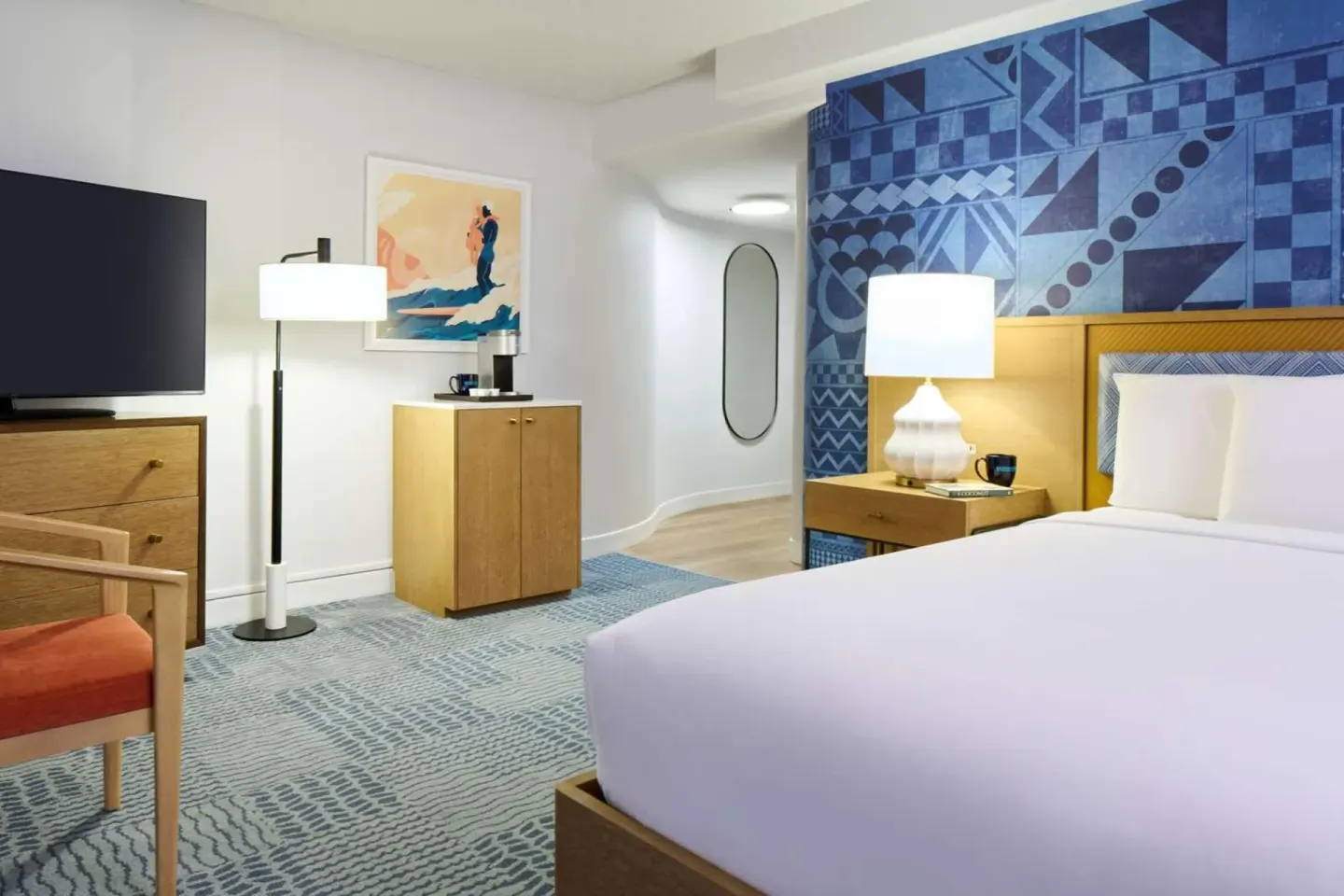 King bed guest room with TV and blue accent wall at OUTRIGGER Waikiki Paradise Hotel.