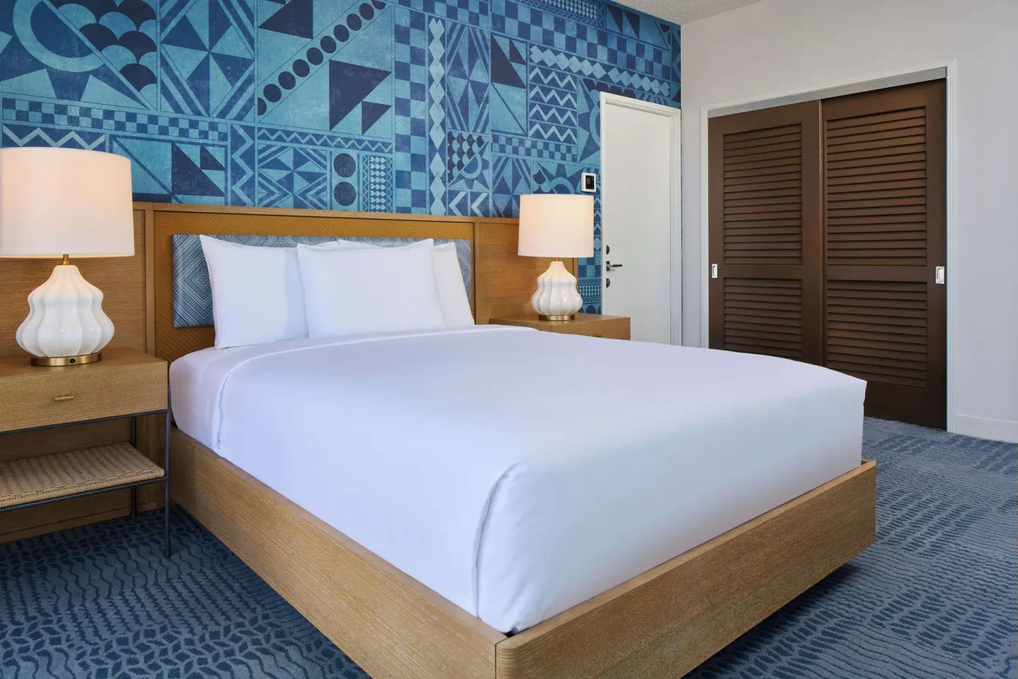 Studio king bed with blue patterned wall at OUTRIGGER Waikiki Paradise Hotel.