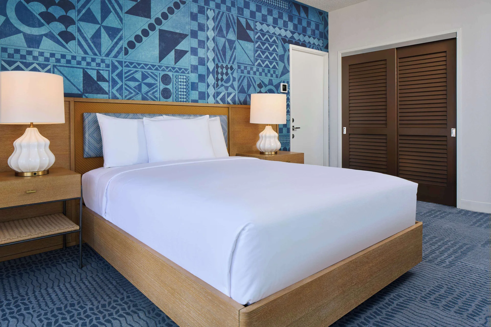 Studio king bed with blue patterned wall at OUTRIGGER Waikiki Paradise Hotel.
