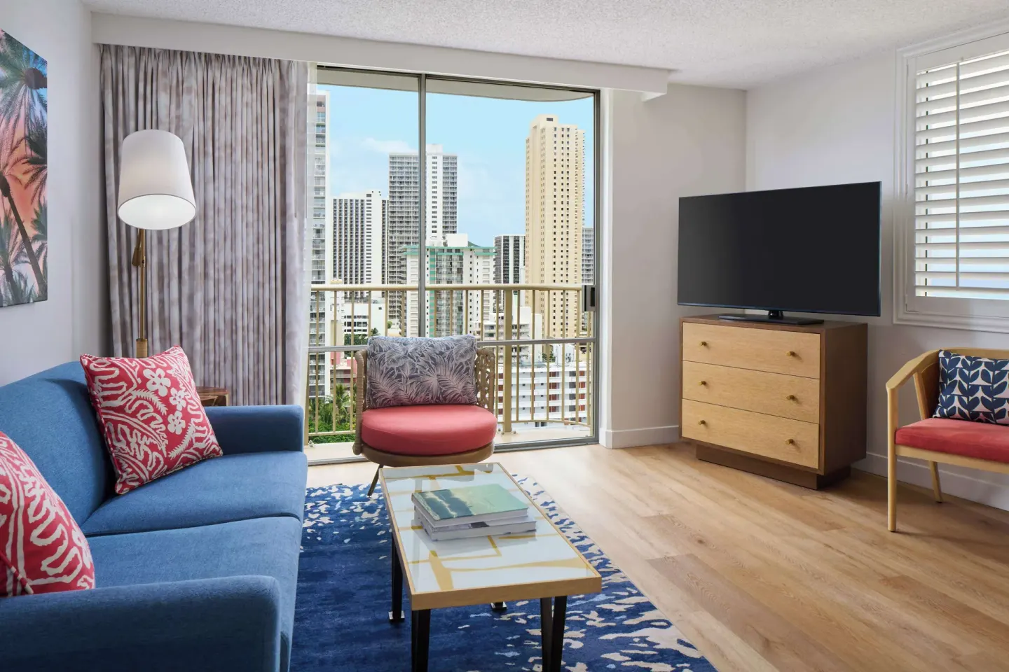 One-bedroom suite living area with balcony and city view at OUTRIGGER Waikiki Paradise Hotel.