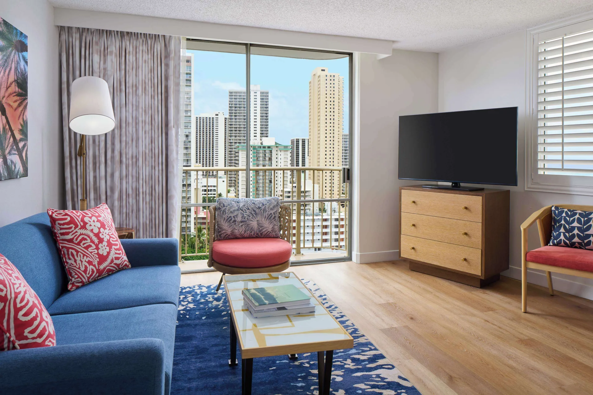 One-bedroom suite living area with balcony and city view at OUTRIGGER Waikiki Paradise Hotel.