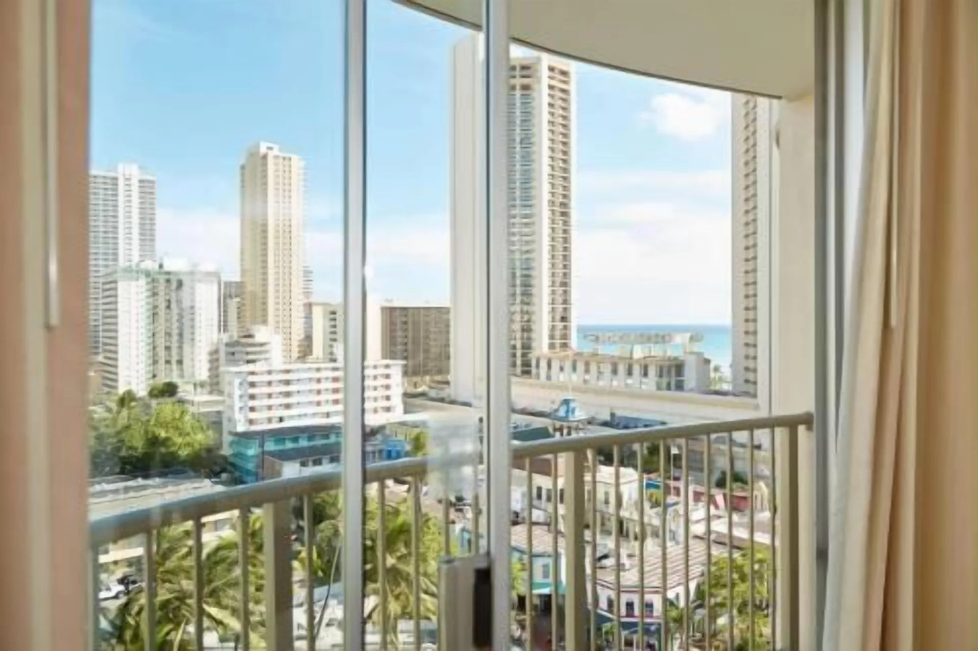 Balcony view with city towers and a glimpse of ocean from OUTRIGGER Waikiki Paradise Hotel.