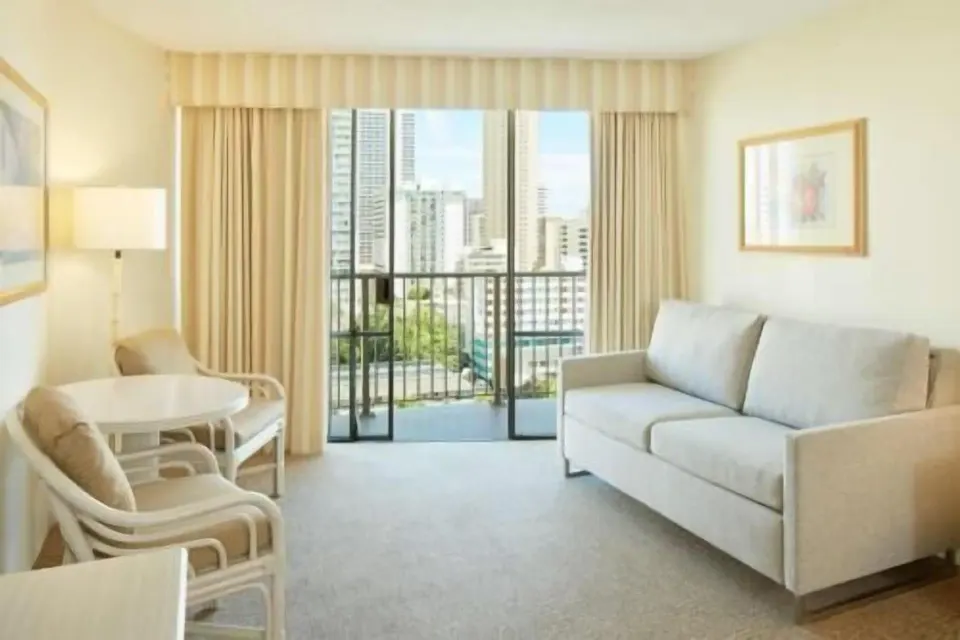 Waikiki Suite View living area with sofa and balcony at OUTRIGGER Waikiki Paradise Hotel.