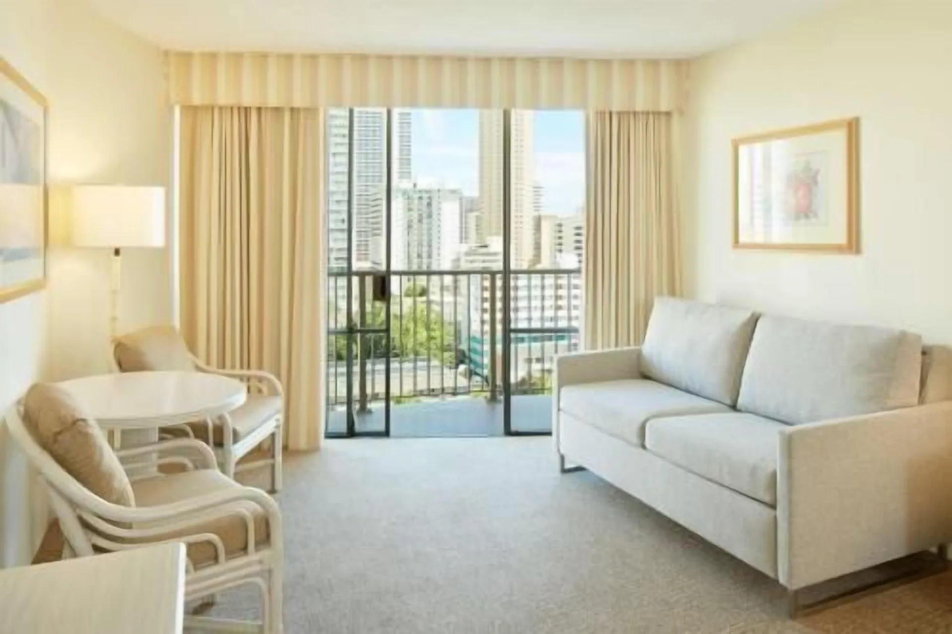 Waikiki Suite View living area with sofa and balcony at OUTRIGGER Waikiki Paradise Hotel.