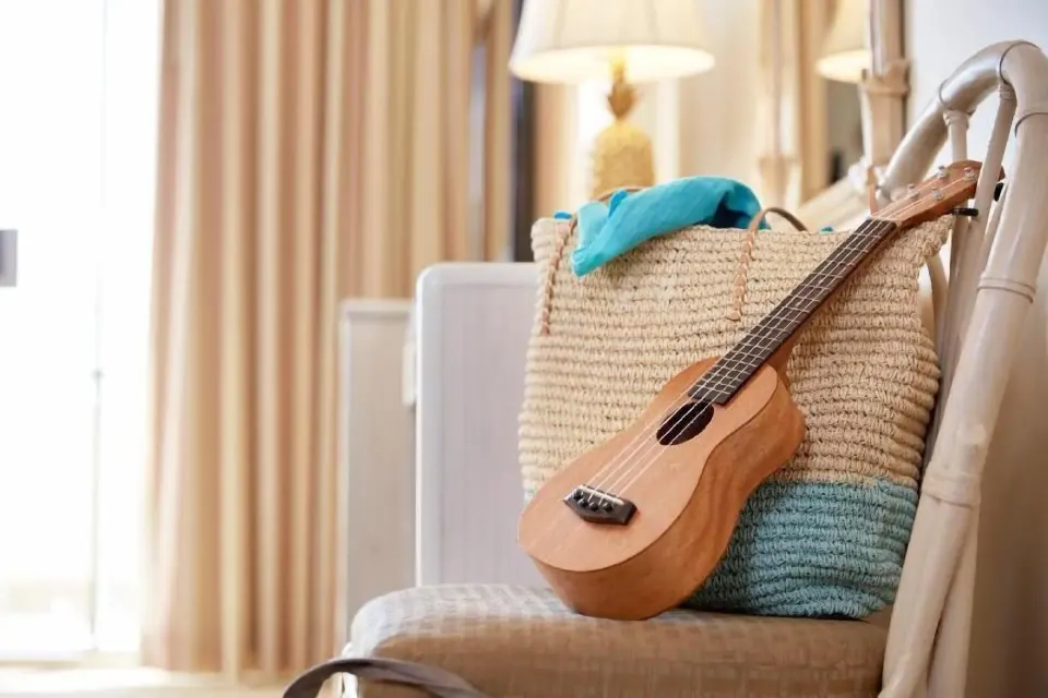 Ukulele and woven beach tote on a chair in a Waikiki Suite at OUTRIGGER Waikiki Paradise Hotel.