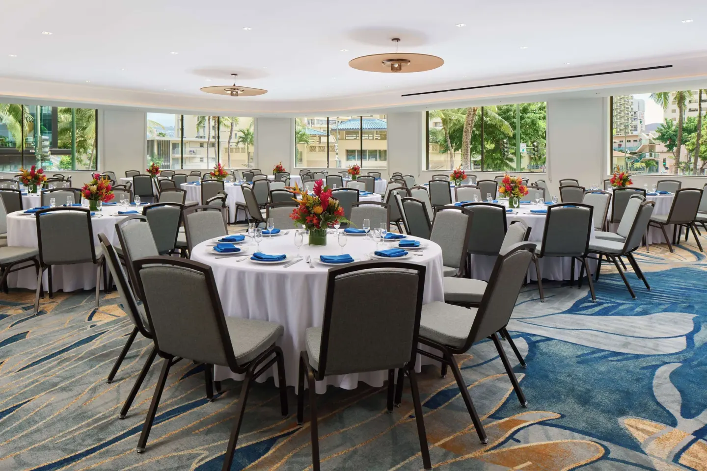Banquet room with round tables set for an event at OUTRIGGER Waikiki Paradise Hotel.