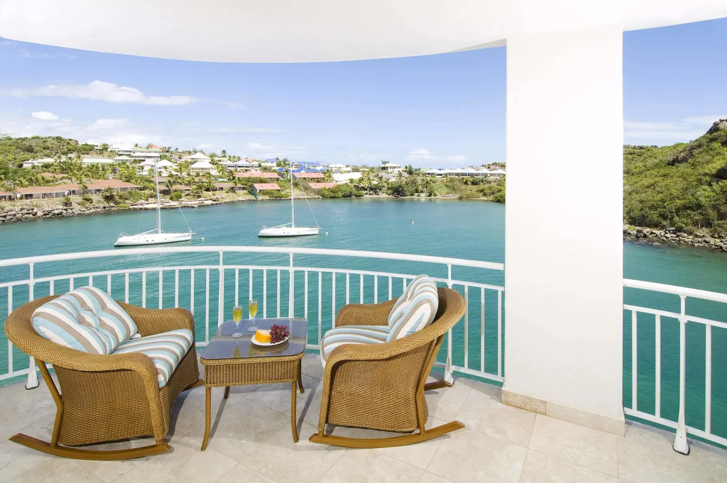 Balcony with wicker chairs overlooking boats at Oyster Bay Beach Resort.