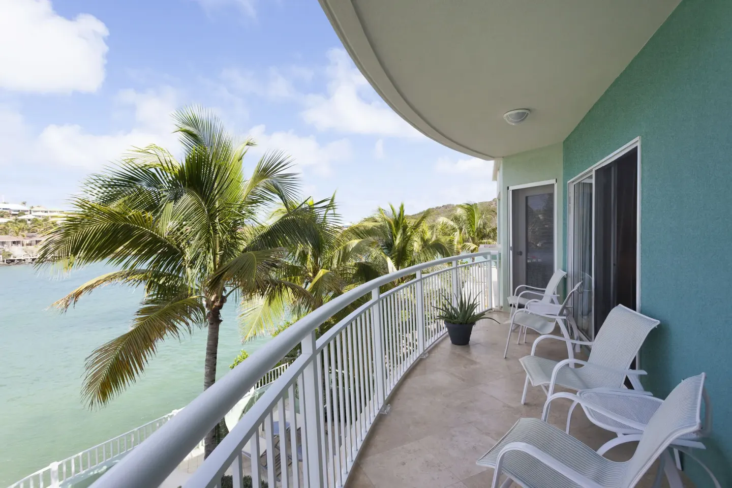 Curved balcony with white chairs and palm views at Oyster Bay Beach Resort.